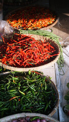 Pile of red chilies, green chilies and cayenne peppers in a bamboo basket. Focus selected