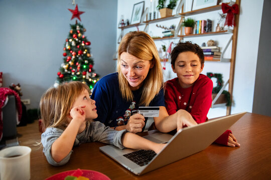 Mom and kids doing Christmas online shopping with laptop and credit card