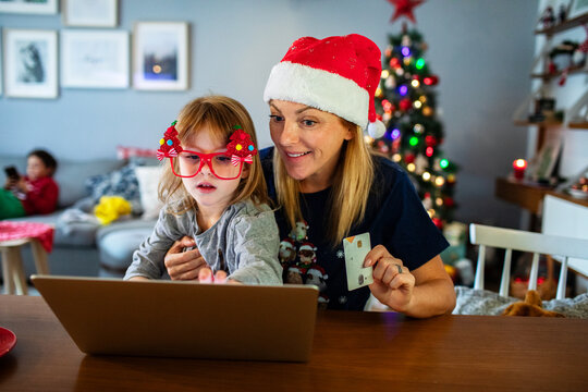 Mom and kid doing Christmas online shopping with laptop and credit card