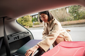 Woman loading luggage into car trunk before travel