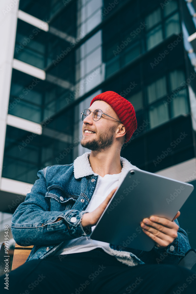Aufkleber positive hipster guy smiling and looking away while creating interesting idea for web blog sitting w