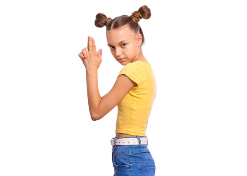 Teen girl in a yellow top with pigtails posing like a spy, making a finger gun gesture, isolated on white background.