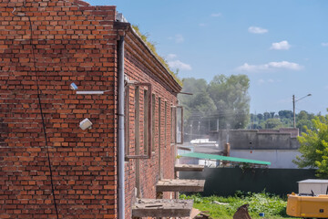 Stary budynek z czerwonej cegły, poddawany procesowi rozbiórki,ze względów bezpieczeństwa, pod błękitnym letnim niebem w lipcowy poranek w mieście (Ostrowiec).