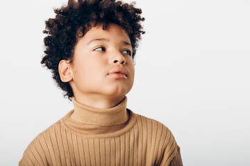 Curlyhaired young boy in a turtleneck sweater gazing upwards with innocence and wonder in his eyes