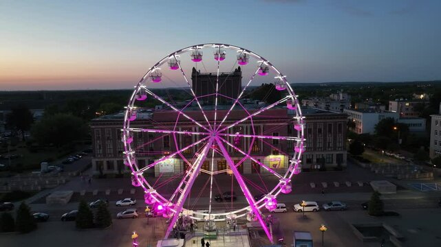 Large colorful Ferris wheel in city center. Aerial drone view on Colorful Ferris wheel spinning in the city center Dabrowa Gornicza Poland. Colorful Ferris wheel From a bird's eye view drone at night.
