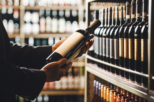 Faceless Person Holds Taking from Shelf Bottle of Wine in Store, Close up