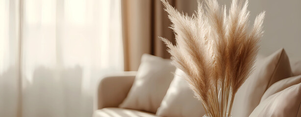 Beige fluffy pampas grass in a beige woven vase on a white sofa with a blurred living room background, in close-up.