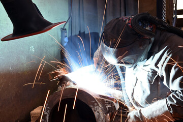Welder in protective clothing at the workplace in an industrial company in steel construction