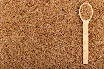 Wooden spoon with flax seeds on flax seeds background