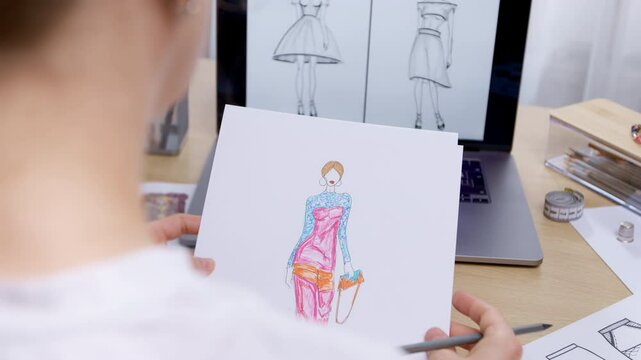 Female fashion designer working with clothes sketches drawn on paper using laptop. Seamstress concept.