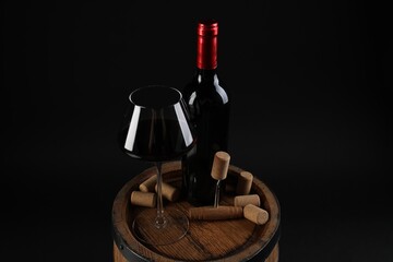 Corkscrew, bottle of wine, glass and corks on wooden barrel against black background