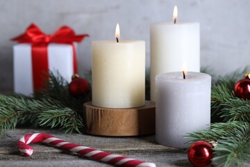Burning candles, Christmas decor and fir tree branches on wooden table, closeup