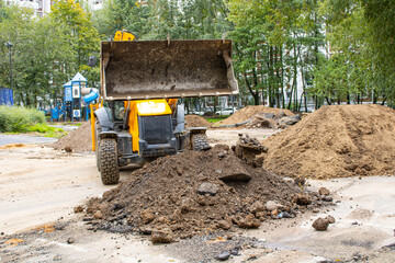 A bulldozer is actively loading soil into a sizable pile on a construction site