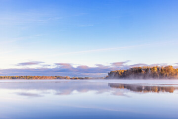Glossy forest lake with water reflections a misty autumn morning