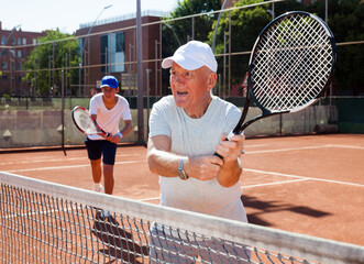 Grandfather and grandson playing tennis court