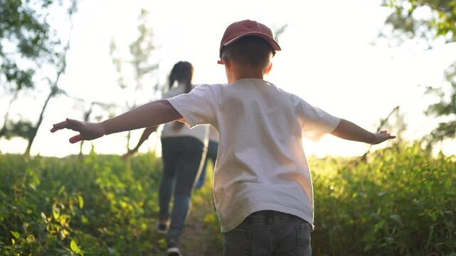 Children running in the forest at sunset. Child happy summer concept. A group of children are playing outside while a man runs. Group of children running in the forest lifestyle playing in the sunset.