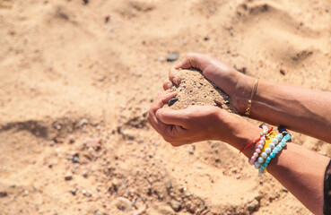 Sand in woman's hands at sea. Selective focus.