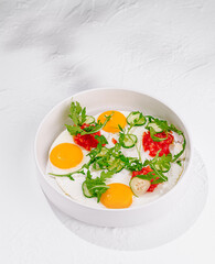 Tasty fried eggs with vegetables and herbs for breakfast