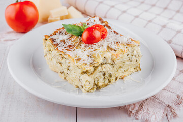 Slice of vegetarian lasagna garnished with fresh ingredients on white plate