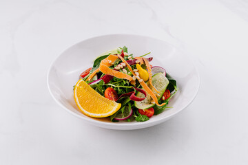 Fresh vegan salad with orange and pine nuts on white background
