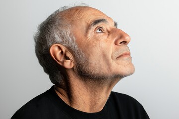 Fototapeta premium A man with a bald head and white hair looking up. The man is wearing a black shirt and has a beard