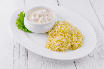 Steaming plate of pasta being served with creamy sauce on white table
