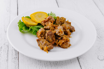 Delicious fried pork meat presenting on white plate with vegetable garnish