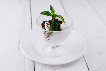 Vanilla ice cream with chocolate sprinkles and mint being served in glass cup