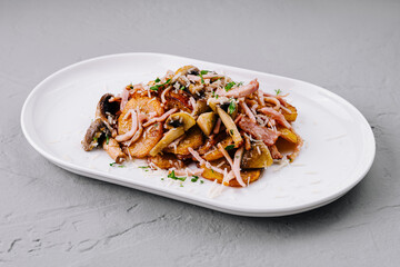 Roasted potatoes with bacon and mushrooms on white plate