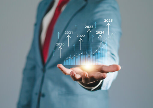 Businessman analyzes market growth trend graph in 2025 and plans business growth and profit increase. Calculates financial data for long-term investment.
