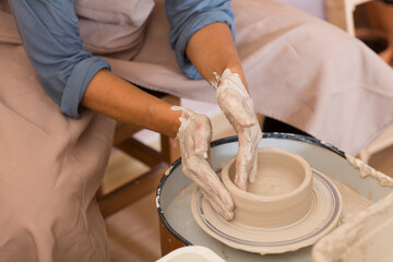 woman hands  moulding clay on pottery wheel. Craftswoman making pot in workshop. Ceramic artist woman.