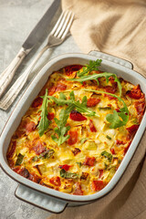 Casserole with zucchini, cheese, eggs, tomatoes, green onions and salmon pieces. Keto.
