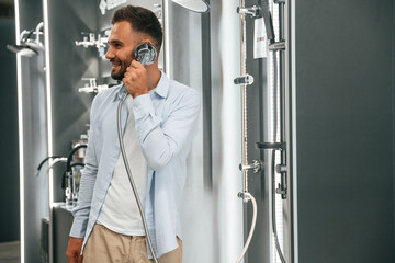 Talking by showerhead, having fun, joking. Man is in the hardware shop