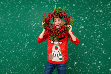 Photo portrait man wearing funny sweater hanging xmas wreath staring crazy isolated green color background