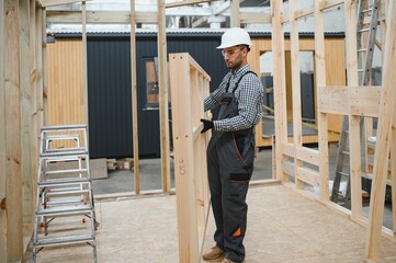 Worker carpenter assembling a modular house