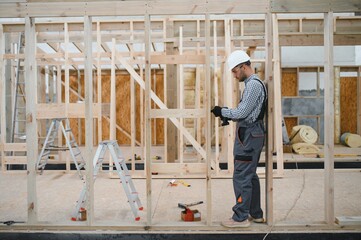 Process of construction new and modern modular house. Worker man in special protective uniform wear...