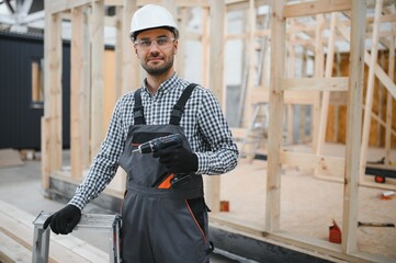 Portrait of a young carpenter worker in a helmet at the construction site of modular houses