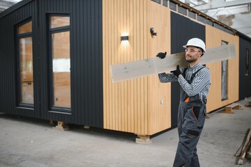 Worker carpenter assembling a modular house