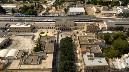Fototapeta premium Aerial view of the train station in Lecce, Puglia, Italy. There are trains stopped at the platforms and passengers ready to leave.