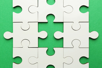 Obraz premium White puzzle pieces on green background, top view