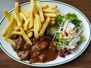 Delicious Belgian Flemish beef stew, called stoofvlees. Authentic local delicacy with beef cooked in wine, served with salad and fries.