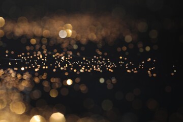 Beautiful shiny golden glitter on black background, closeup