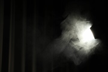 Professional spotlight and smoke against curtain in darkness. Space for text