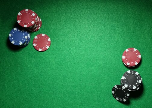 Poker chips on green table, flat lay. Space for text