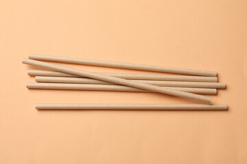 Bamboo drinking straws on beige background, top view