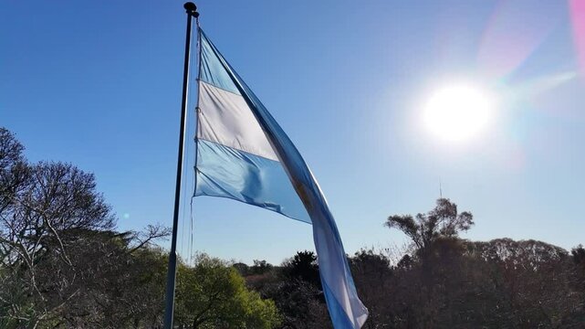 bandera argentina flameando sobre sol, cielo azul	
