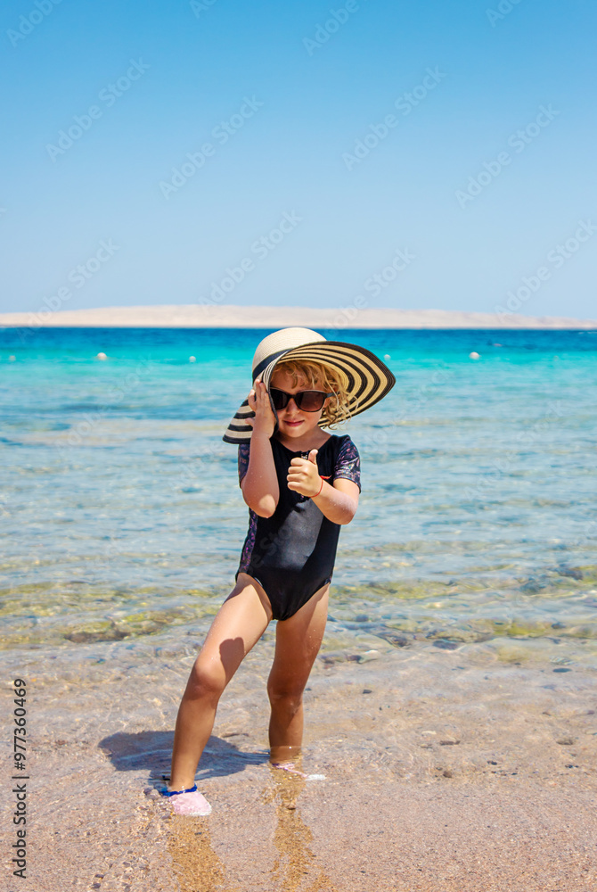 Poster Children on the beach in a hat. Selective focus.