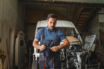 Car mechanic in workshop with unfinished car maintenance work