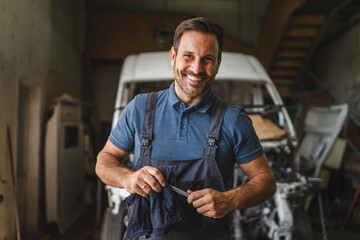 Car mechanic in workshop with unfinished car maintenance work