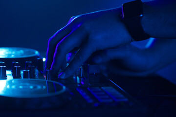 DJ's Hand on Mixer in Blue Light